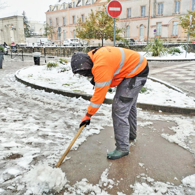 Agent municipal déneigeant le trottoir