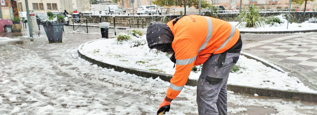 Agent municipal déneigeant le trottoir